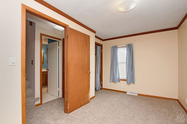 unfurnished bedroom with light carpet, a textured ceiling, and ornamental molding