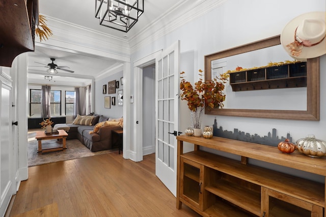 interior space featuring crown molding, french doors, ceiling fan with notable chandelier, and light wood-type flooring