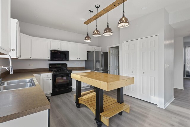 kitchen with sink, white cabinets, hanging light fixtures, light hardwood / wood-style floors, and black appliances