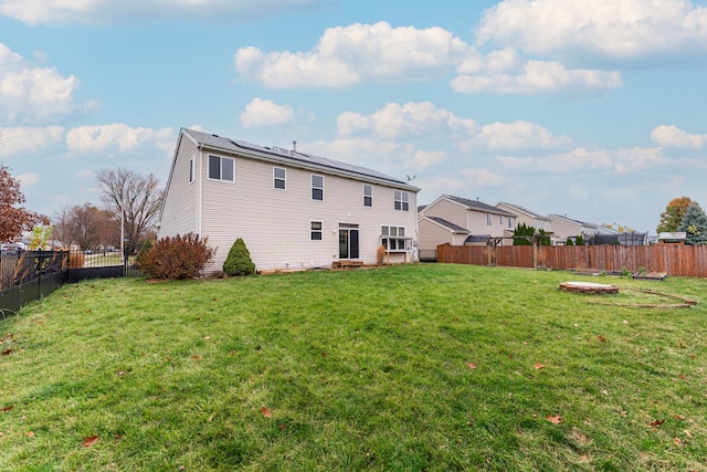 back of property with a yard and solar panels