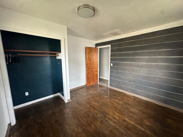 unfurnished bedroom with dark hardwood / wood-style floors, a closet, and crown molding