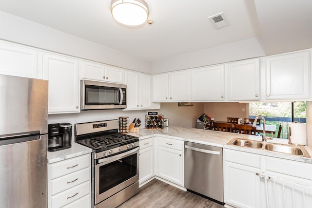 kitchen featuring sink, light hardwood / wood-style floors, white cabinets, and appliances with stainless steel finishes