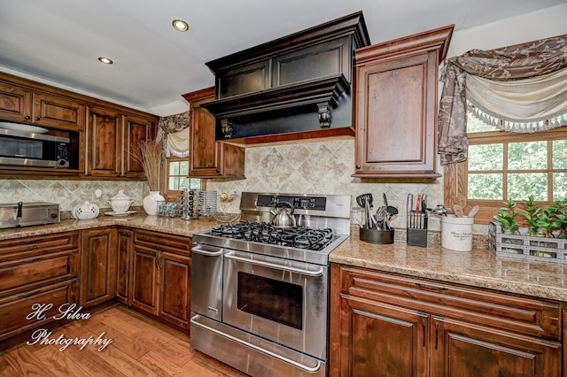 kitchen featuring light stone countertops, appliances with stainless steel finishes, light hardwood / wood-style floors, and a healthy amount of sunlight