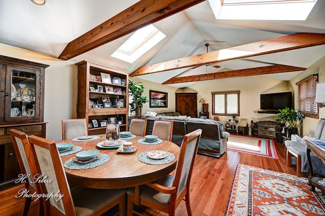 dining room with vaulted ceiling with skylight and light hardwood / wood-style floors