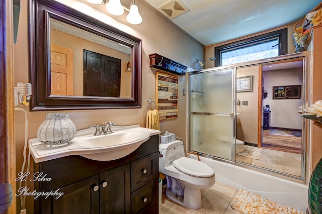 full bathroom with shower / bath combination with glass door, vanity, toilet, and tile patterned flooring