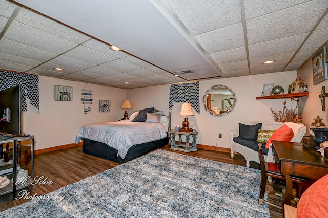 bedroom featuring a drop ceiling and dark wood-type flooring