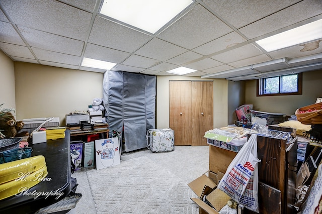 basement with a drop ceiling and light colored carpet