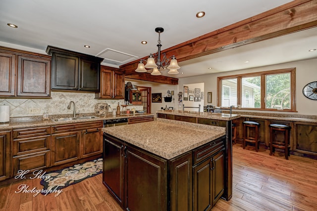 kitchen featuring dark brown cabinetry, a kitchen island, light hardwood / wood-style floors, and decorative light fixtures