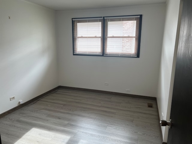 spare room featuring crown molding and light hardwood / wood-style flooring