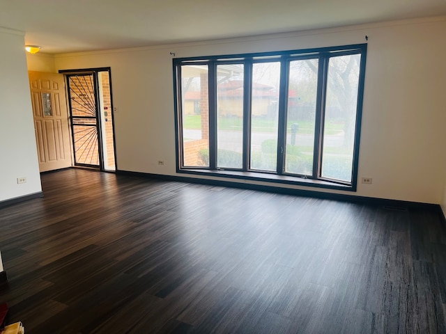 empty room with dark hardwood / wood-style flooring and crown molding