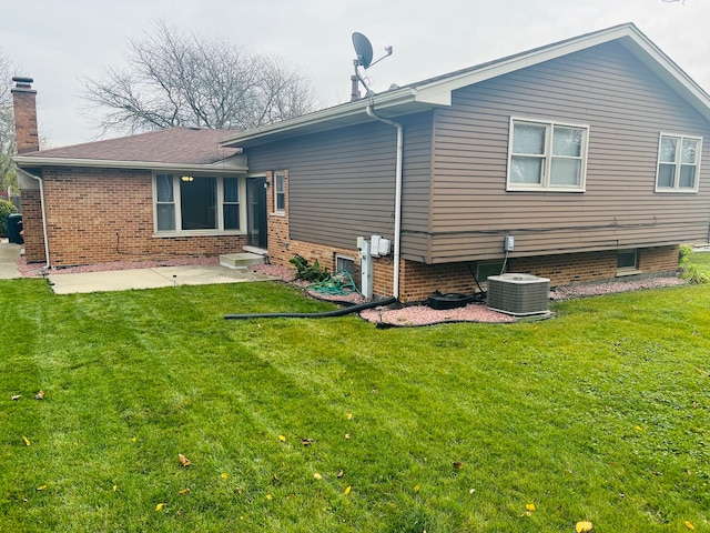 rear view of property featuring a patio, cooling unit, and a lawn