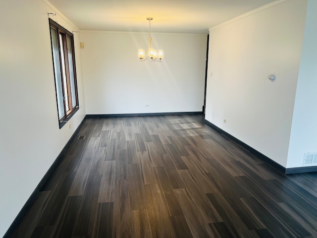 spare room with a notable chandelier, dark hardwood / wood-style floors, and crown molding