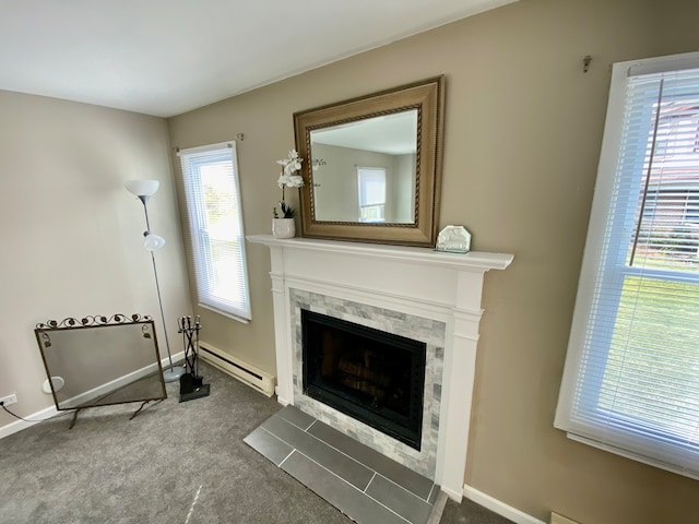 interior space featuring a fireplace, dark colored carpet, a wealth of natural light, and a baseboard heating unit