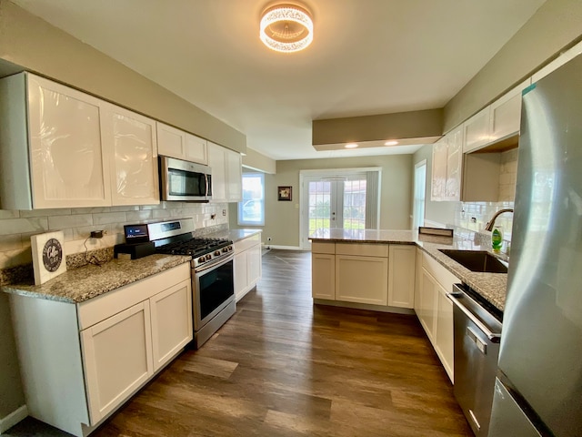 kitchen with dark wood-type flooring, sink, appliances with stainless steel finishes, white cabinetry, and kitchen peninsula