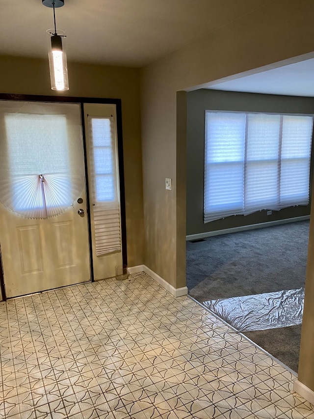 foyer entrance with light colored carpet and a healthy amount of sunlight