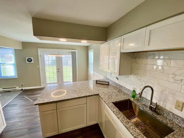 kitchen featuring kitchen peninsula, light stone countertops, dark hardwood / wood-style flooring, a baseboard heating unit, and sink