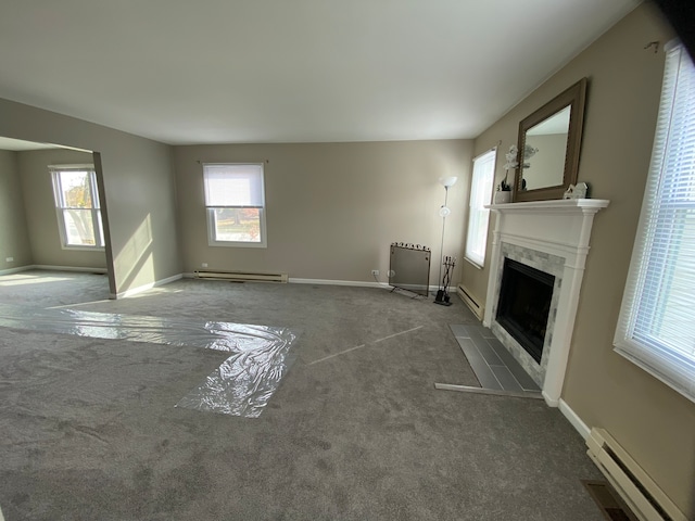 unfurnished living room featuring a wealth of natural light, carpet floors, and a baseboard radiator