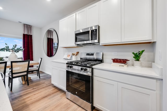 kitchen featuring stainless steel appliances, white cabinetry, light hardwood / wood-style floors, and light stone counters