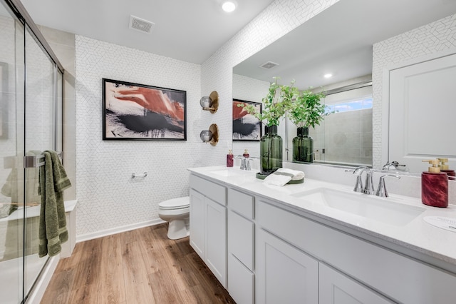 bathroom with toilet, hardwood / wood-style flooring, tile walls, a shower with door, and vanity