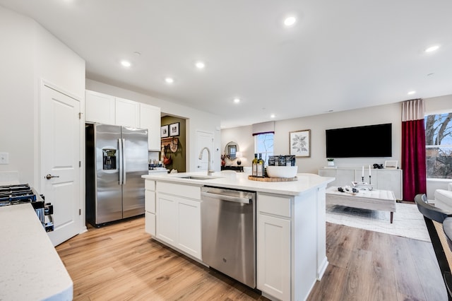 kitchen featuring white cabinets, a center island with sink, appliances with stainless steel finishes, and sink