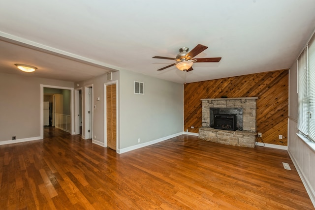 unfurnished living room with wood walls, ceiling fan, and hardwood / wood-style flooring