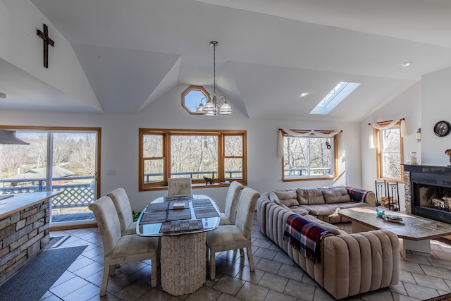 tiled dining space featuring a stone fireplace, lofted ceiling with skylight, and a chandelier