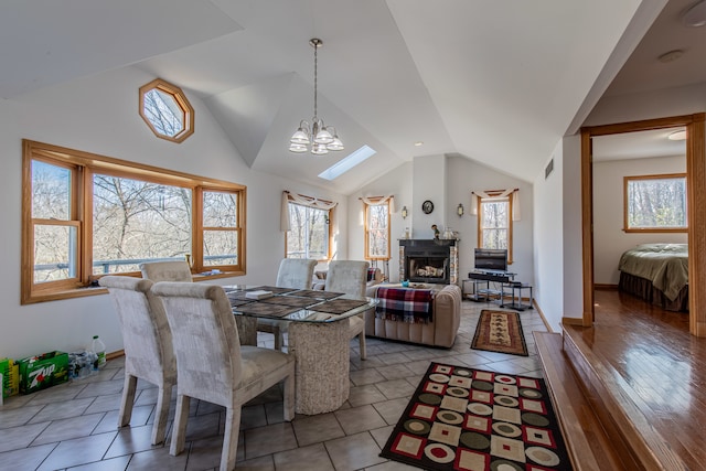 dining space featuring wood-type flooring, a wealth of natural light, a notable chandelier, and vaulted ceiling with skylight