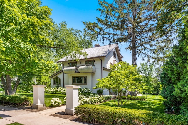 view of front of property featuring a balcony and a front lawn