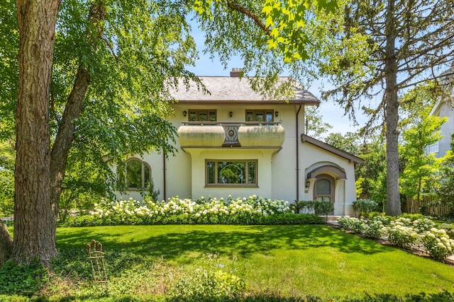 mediterranean / spanish-style house featuring a balcony and a front lawn