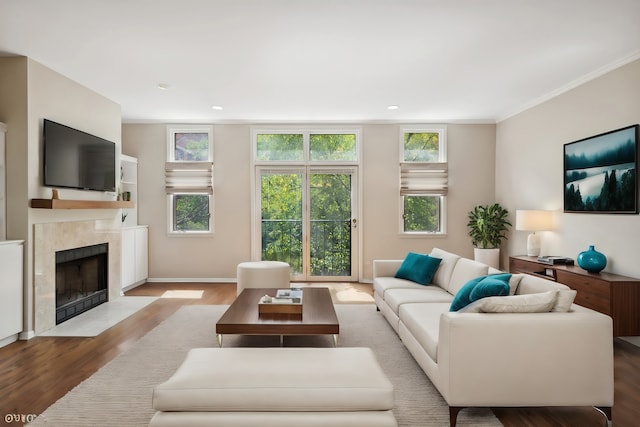 living room with light hardwood / wood-style floors, crown molding, and a tiled fireplace