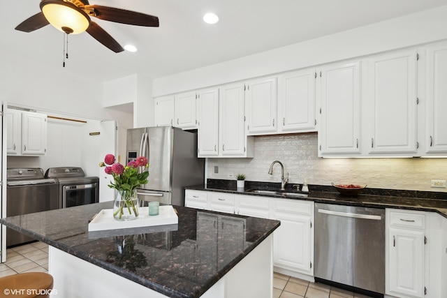 kitchen featuring white cabinets, sink, separate washer and dryer, a kitchen island, and stainless steel appliances