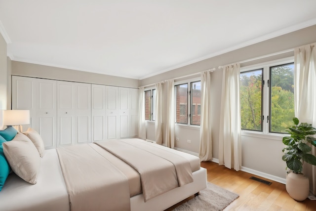 bedroom with light hardwood / wood-style floors, a closet, and ornamental molding