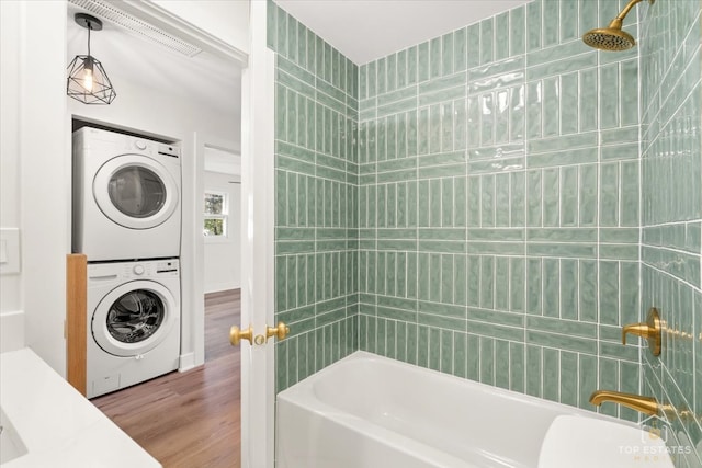 laundry area with stacked washing maching and dryer and hardwood / wood-style flooring