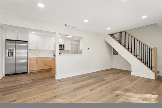 kitchen with white cabinetry, light hardwood / wood-style flooring, light brown cabinets, and appliances with stainless steel finishes