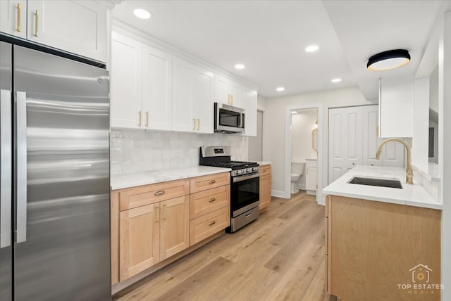 kitchen featuring light brown cabinetry, stainless steel appliances, sink, light hardwood / wood-style flooring, and white cabinetry