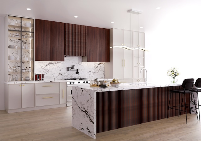 kitchen featuring backsplash, a breakfast bar area, white gas range, light wood-style flooring, and modern cabinets