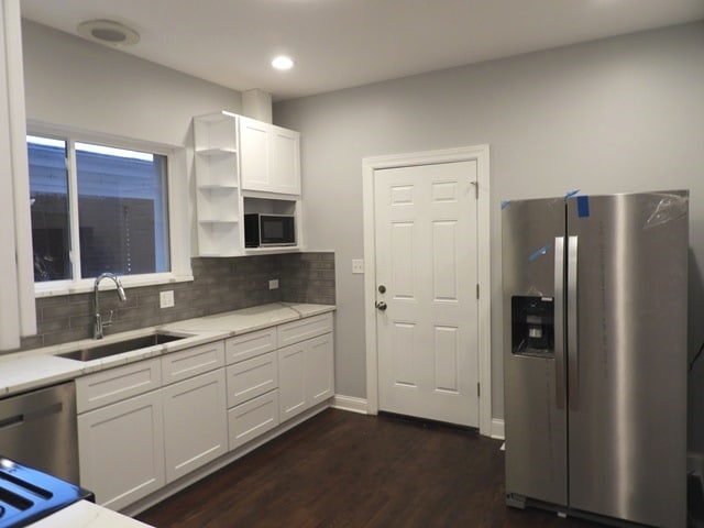 kitchen featuring dark wood-type flooring, white cabinets, sink, appliances with stainless steel finishes, and tasteful backsplash