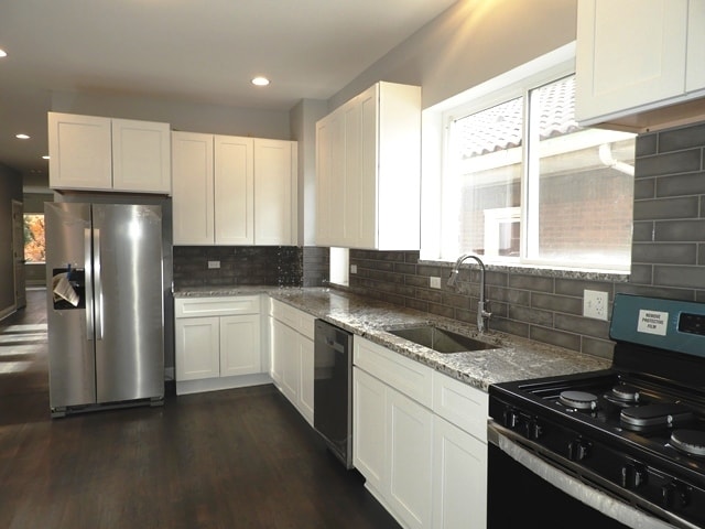 kitchen featuring sink, tasteful backsplash, dark hardwood / wood-style floors, white cabinets, and appliances with stainless steel finishes