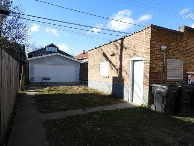 view of side of property with a garage, an outdoor structure, and a lawn