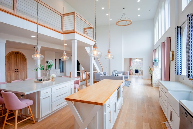 kitchen with white cabinetry, a large island, a high ceiling, pendant lighting, and light hardwood / wood-style floors