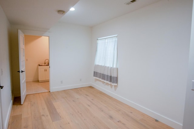 spare room with light hardwood / wood-style floors and sink