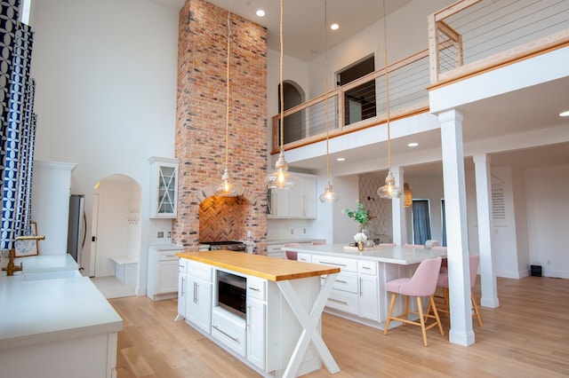 kitchen featuring a kitchen bar, white cabinetry, a towering ceiling, and a kitchen island