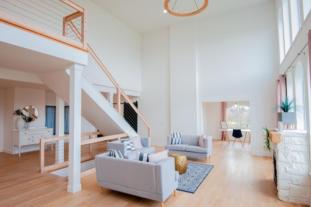 living room featuring a notable chandelier, light hardwood / wood-style floors, and a high ceiling