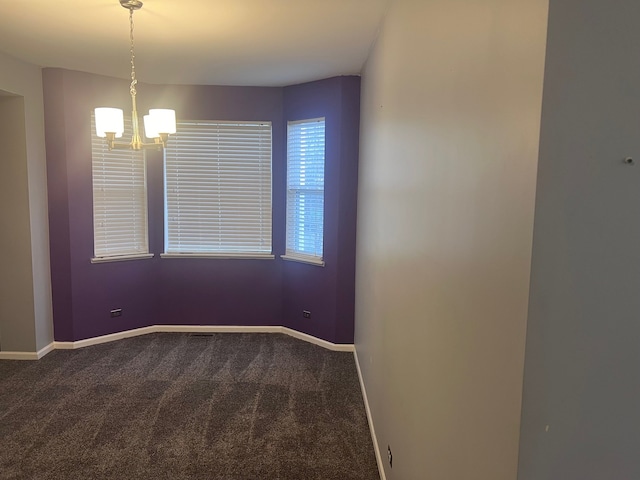 empty room featuring a chandelier, dark carpet, and baseboards