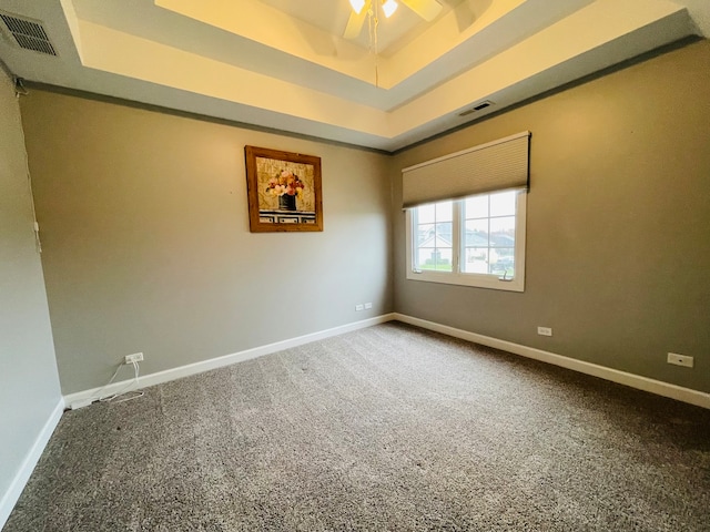 spare room featuring ceiling fan, a raised ceiling, and carpet floors