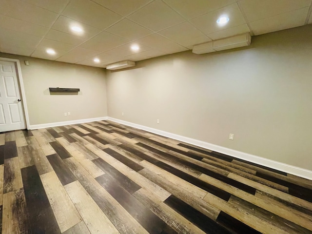 basement with a paneled ceiling and hardwood / wood-style floors