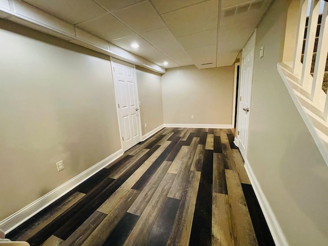 basement featuring dark hardwood / wood-style floors and a drop ceiling