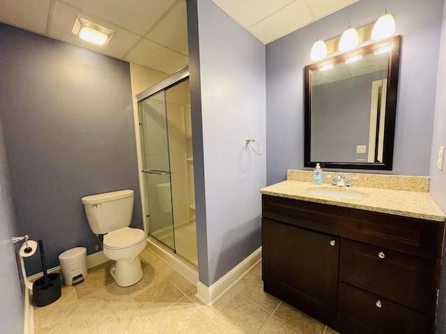 bathroom featuring a paneled ceiling, vanity, a shower with door, tile patterned flooring, and toilet