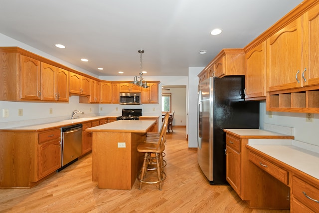 kitchen with stainless steel appliances, sink, a center island, light hardwood / wood-style floors, and hanging light fixtures