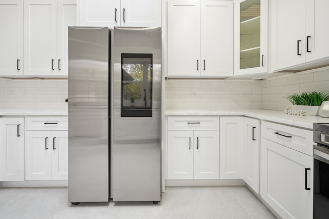 kitchen featuring stainless steel fridge, light tile patterned floors, and white cabinetry